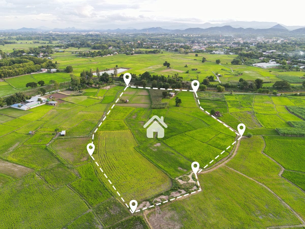 Vista aérea de área verde demarcada com ícones de localização para como comprar um terreno.