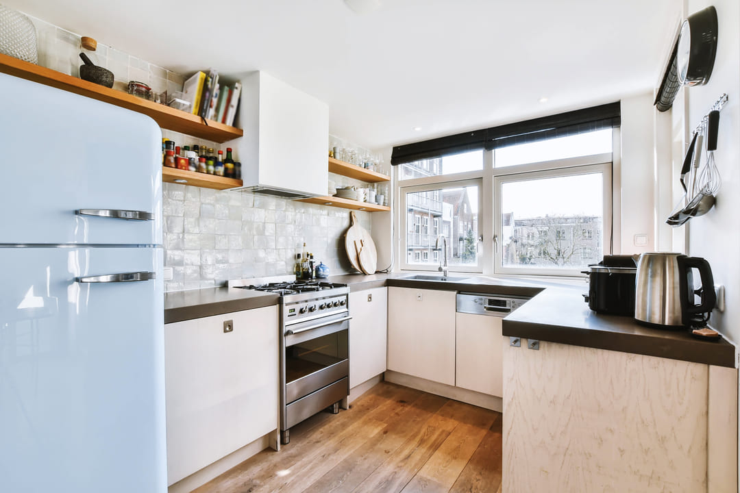 cozinha-pequena: uma cozinha com os móveis branco e o chão com piso de madeira. 