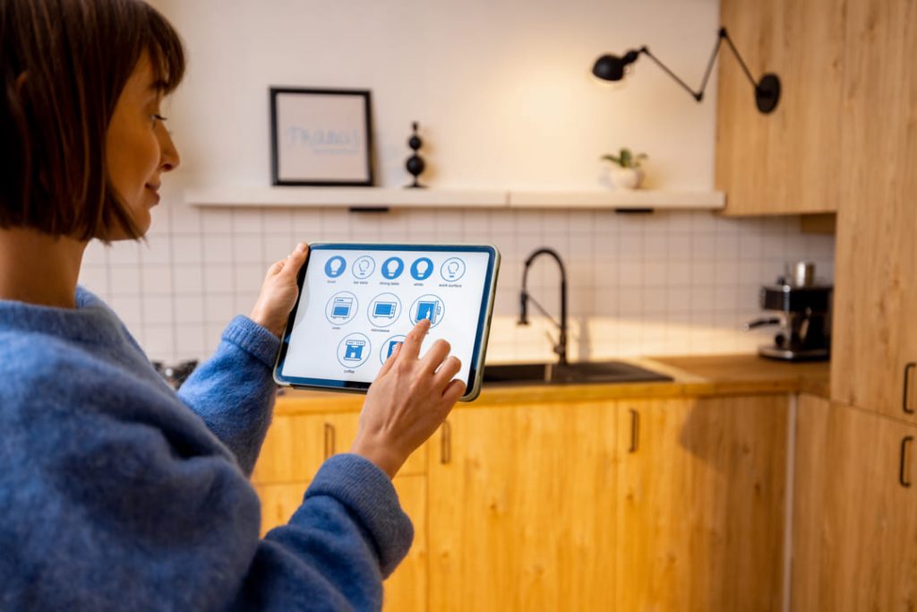 Smart Home: uma mulher de blusa de frio azul mexendo no tablet para controlar sua casa inteligente. 