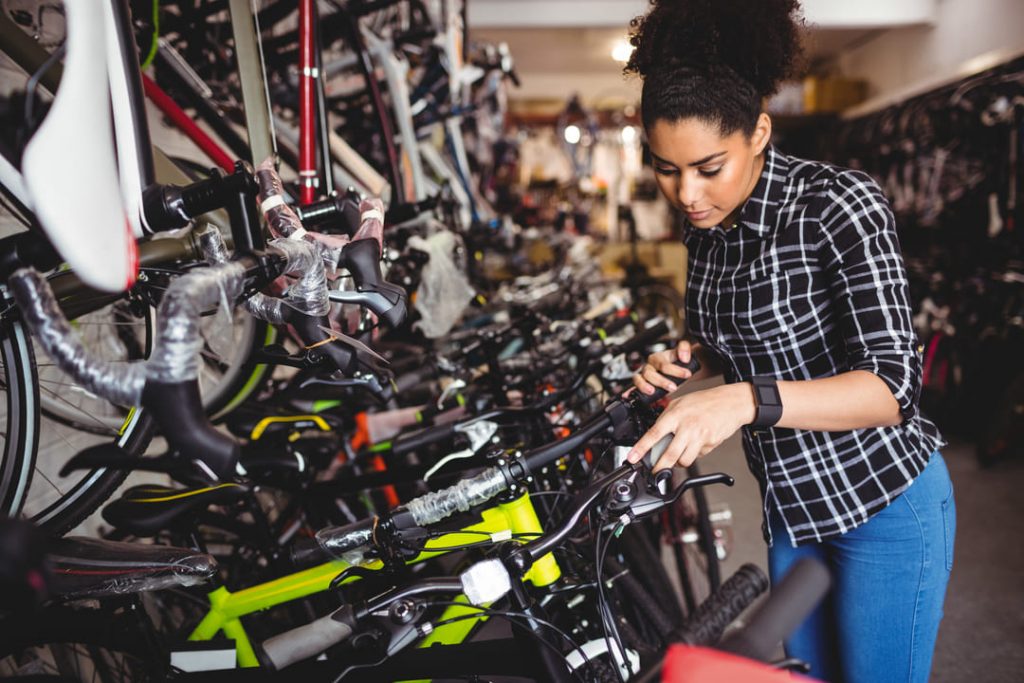 consórcio de bike: uma mulher negra escolhendo uma bicicleta para comprar e na loja há vários modelos. 