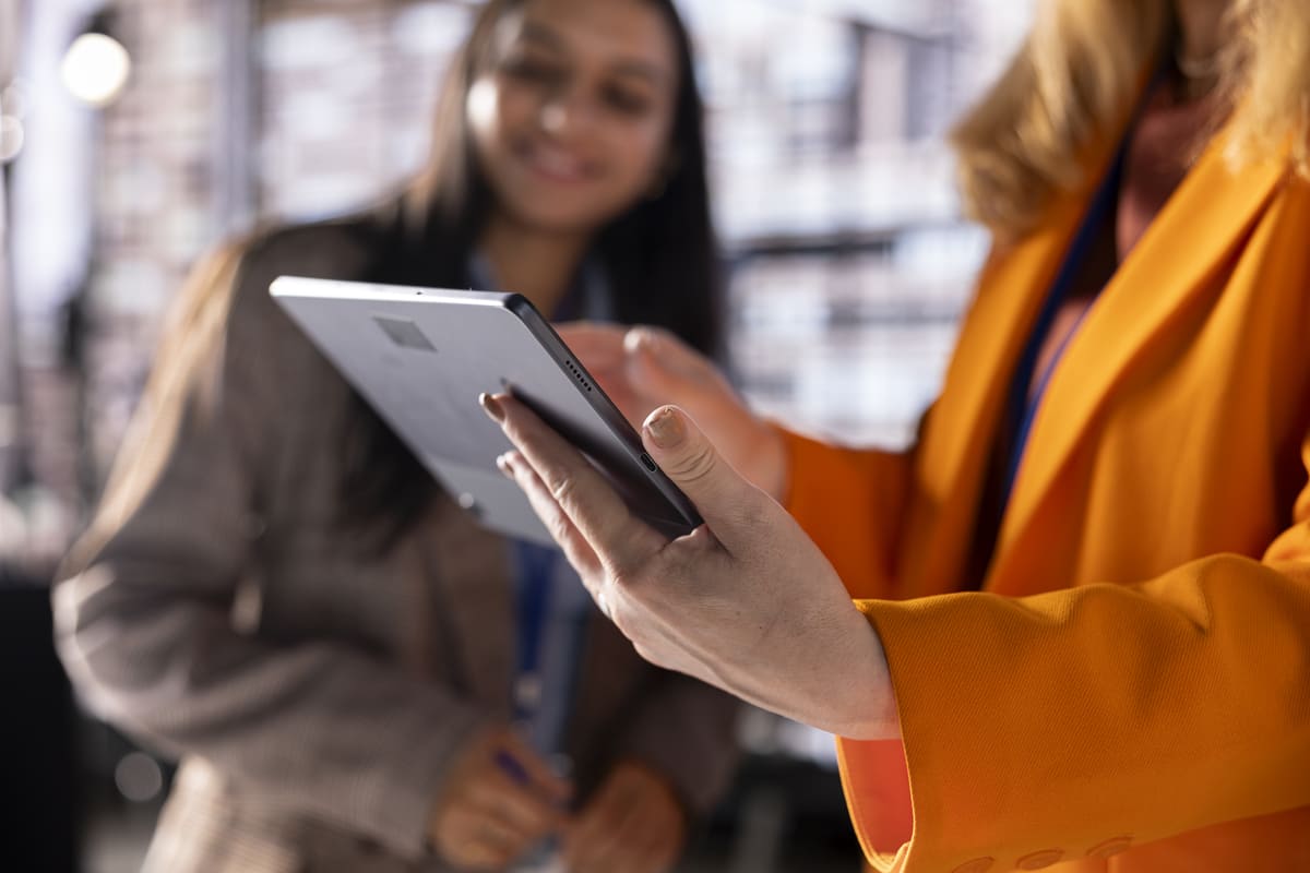 Duas profissionais analisam uma simulação digital no tablet, representando a etapa de aprovação da carta de crédito para serviços.