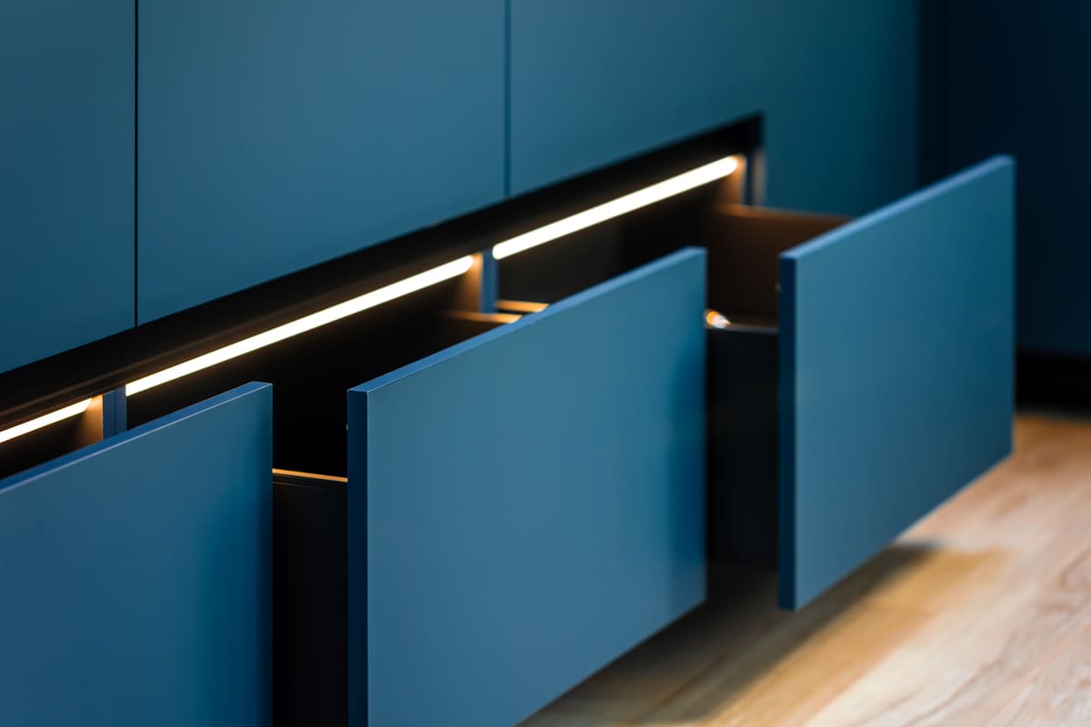 Detalhe de gavetas azuis com iluminação LED interna, destacando a funcionalidade e o acabamento de como comprar móveis planejados.