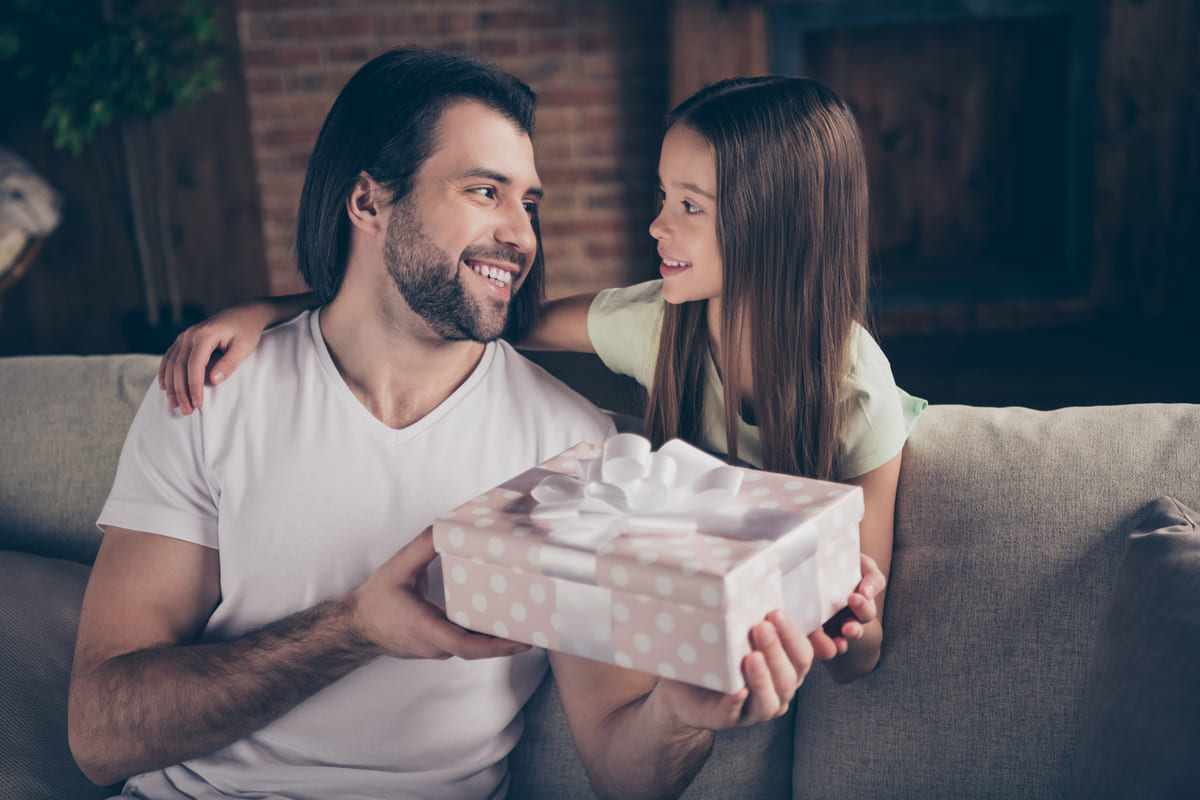 Pai sorrindo ao receber um presente para o Dia dos Pais de sua filha, momento especial de carinho e conexão familiar.