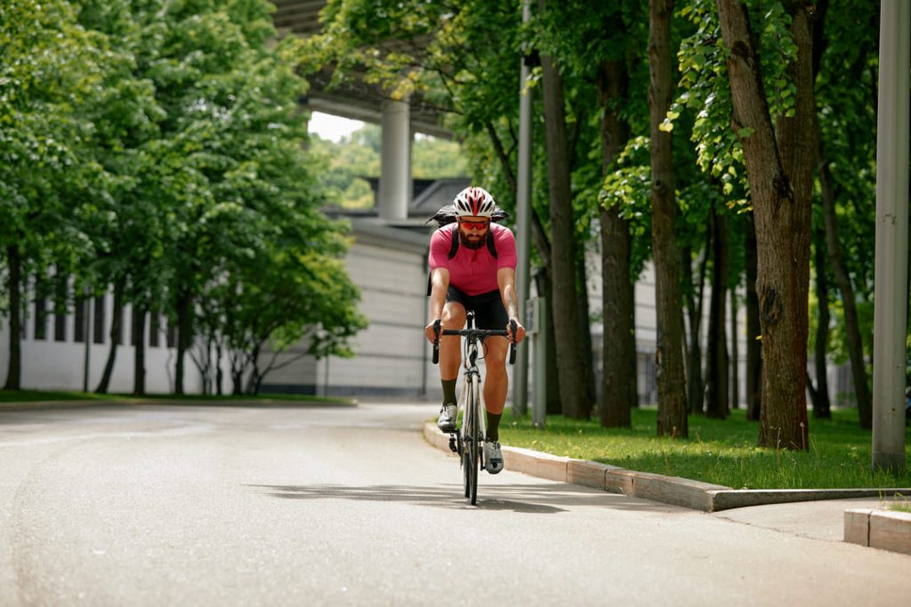 Homem de óculos escuros pedalando ao andar de bicicleta.