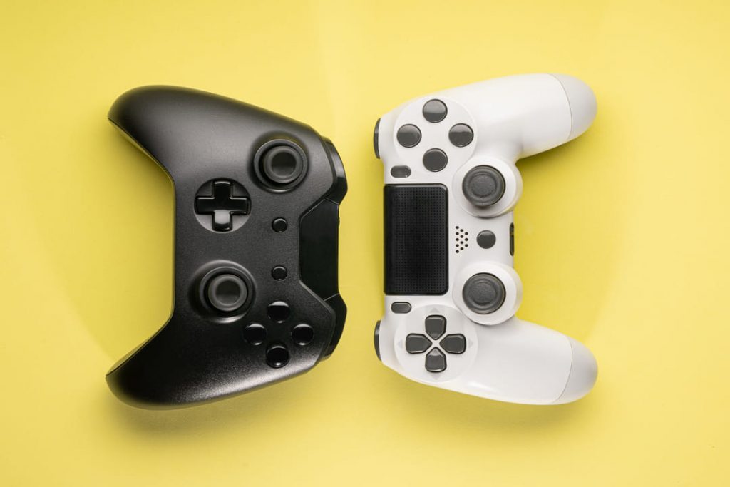 consoles de videogame: um controle preto de xbok e um branco de ps.