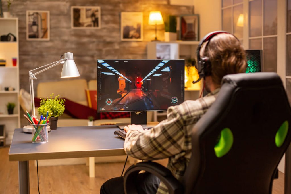 Quarto gamer: um homem jogando no computador em seu quarto.