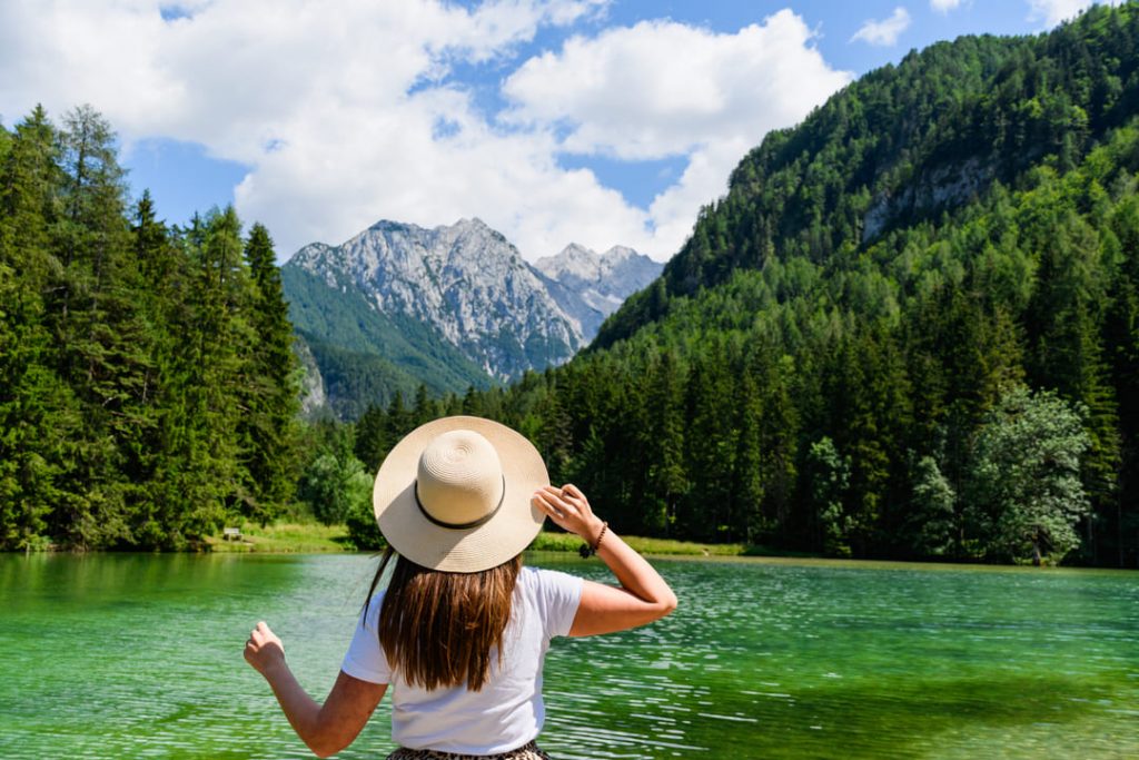 Suíça: uma mulher apreciando a bela paisagem, com uma montanha coberta de neve, um rio e várias árvores.