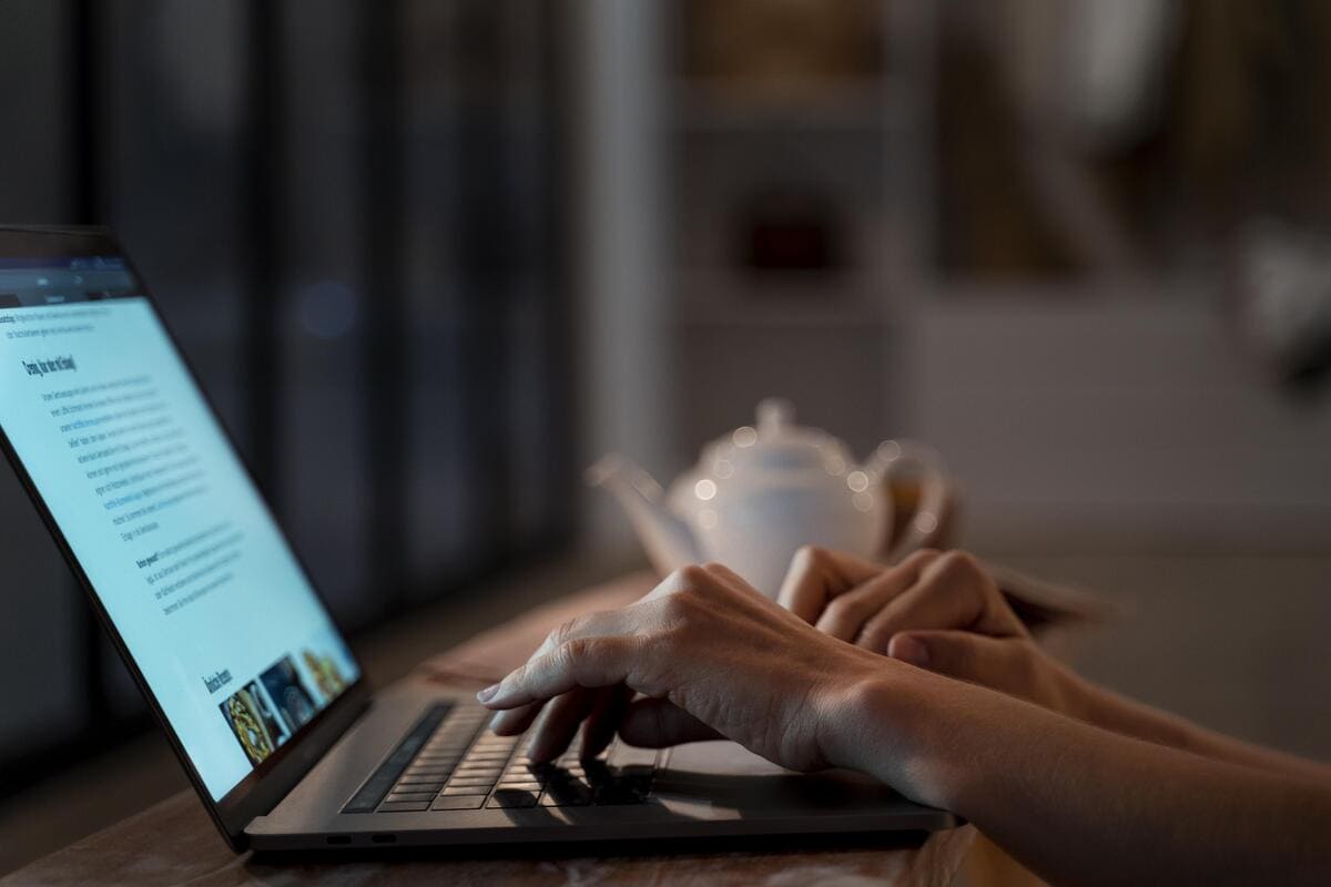 Mãos de pessoa que sabe como ganhar dinheiro com a internet digitando em notebook.
