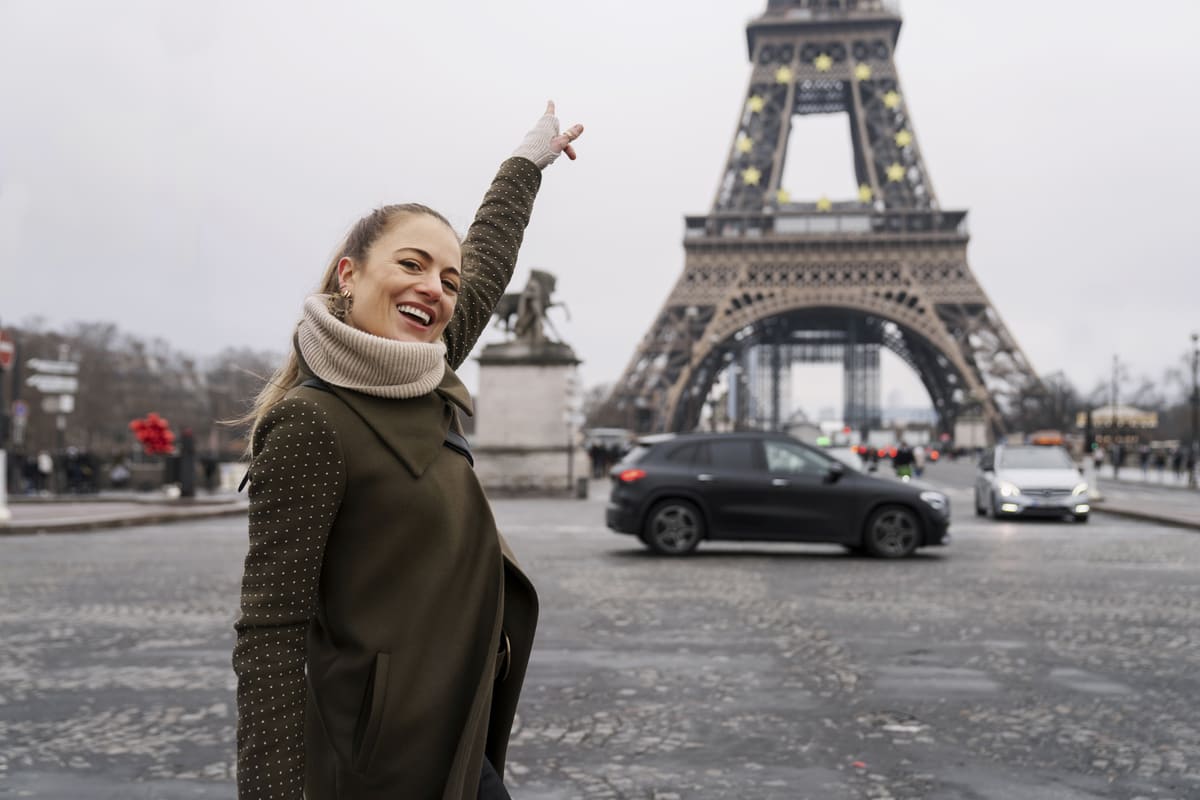Mulher tirando foto apontando para a Torre Eiffel, um dos destinos mais desejados por quem vai fazer a primeira viagem à Europa.