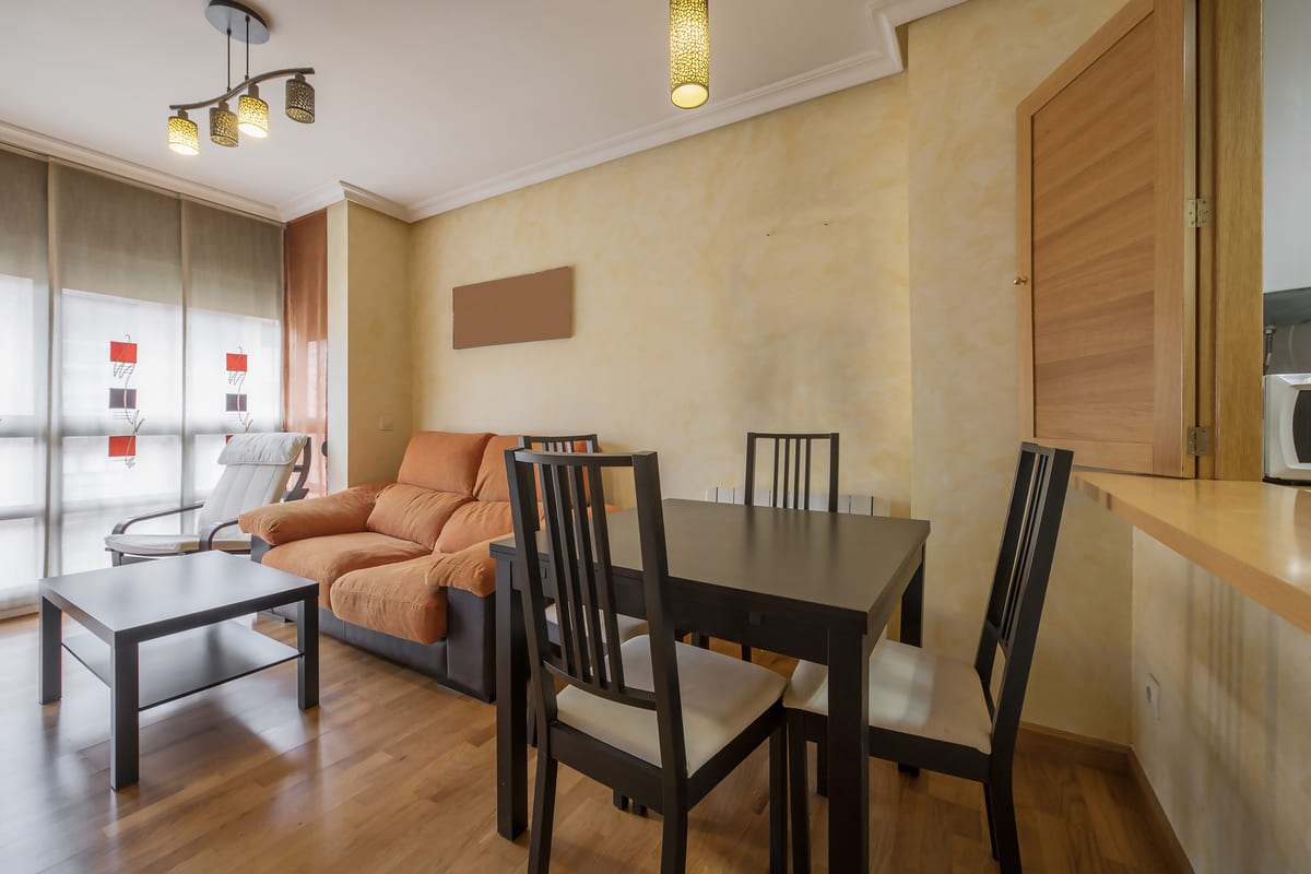 Sala de estar e jantar integradas, mostrando como mobiliar apartamento pequeno de forma funcional com um sofá, mesa de centro e uma mesa de jantar compacta.