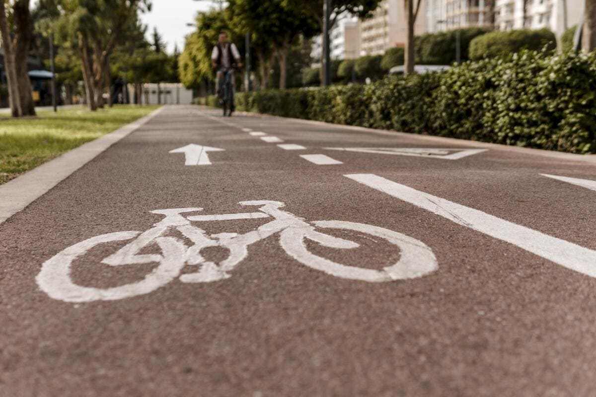Ciclovia sinalizada no asfalto com um ciclista desfocado ao fundo, ilustrando a infraestrutura e a qualidade de vida procuradas nas melhores cidades do interior de SP.