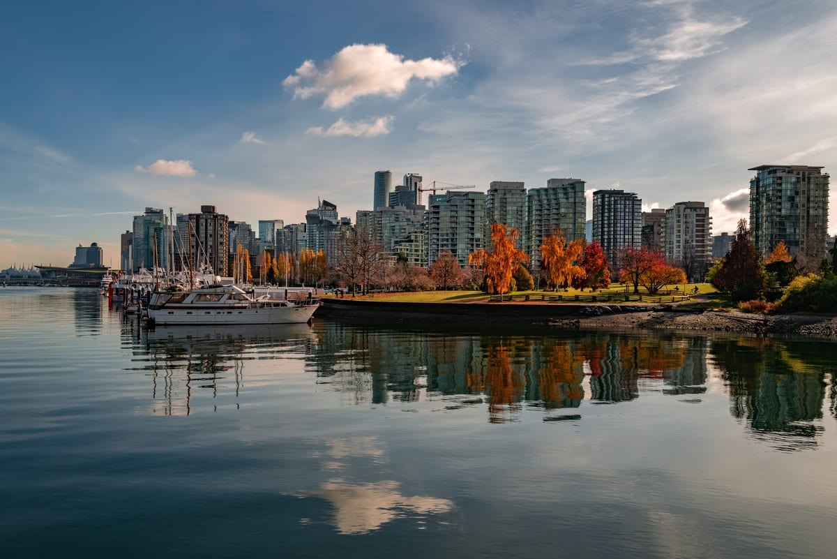 Vista de prédios e árvores refletidos na água de cidade em guia com tudo sobre o Canadá.