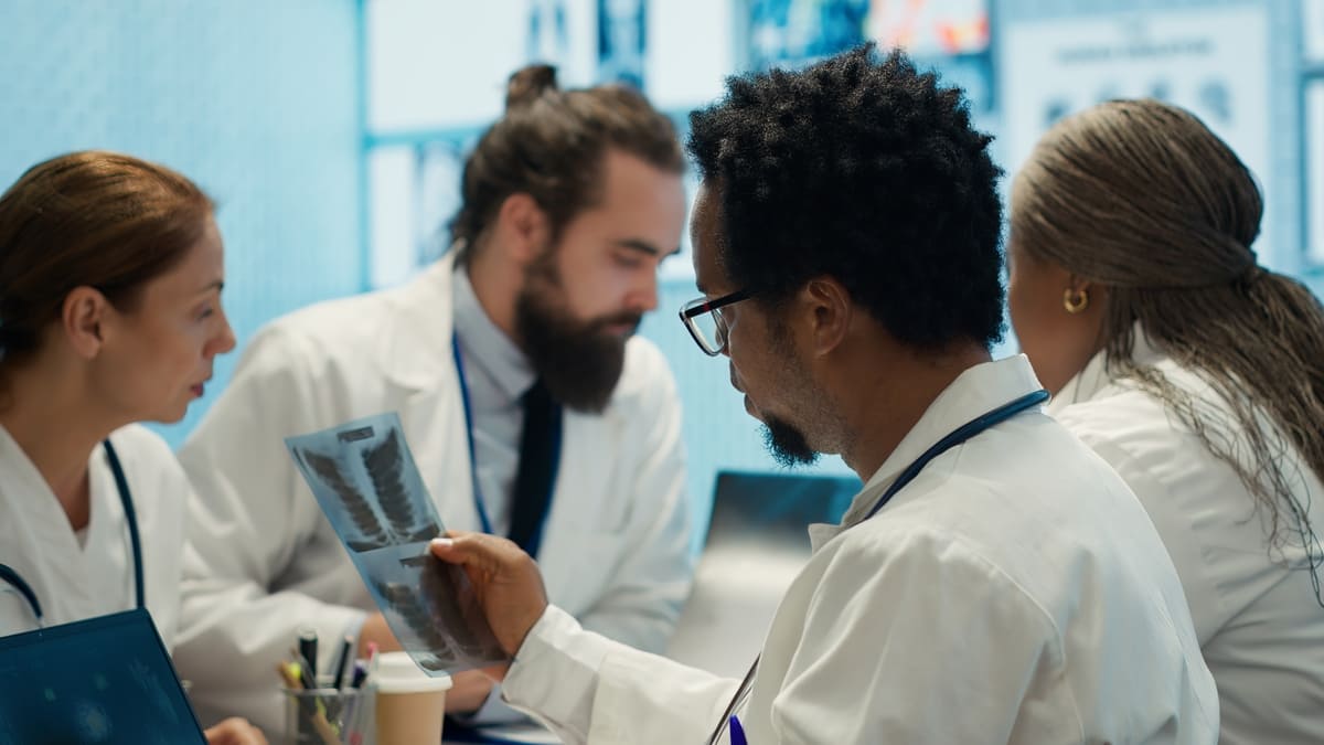 Médicos de jaleco analisam raio-X de tórax, atividade comum nas melhores universidades do mundo.