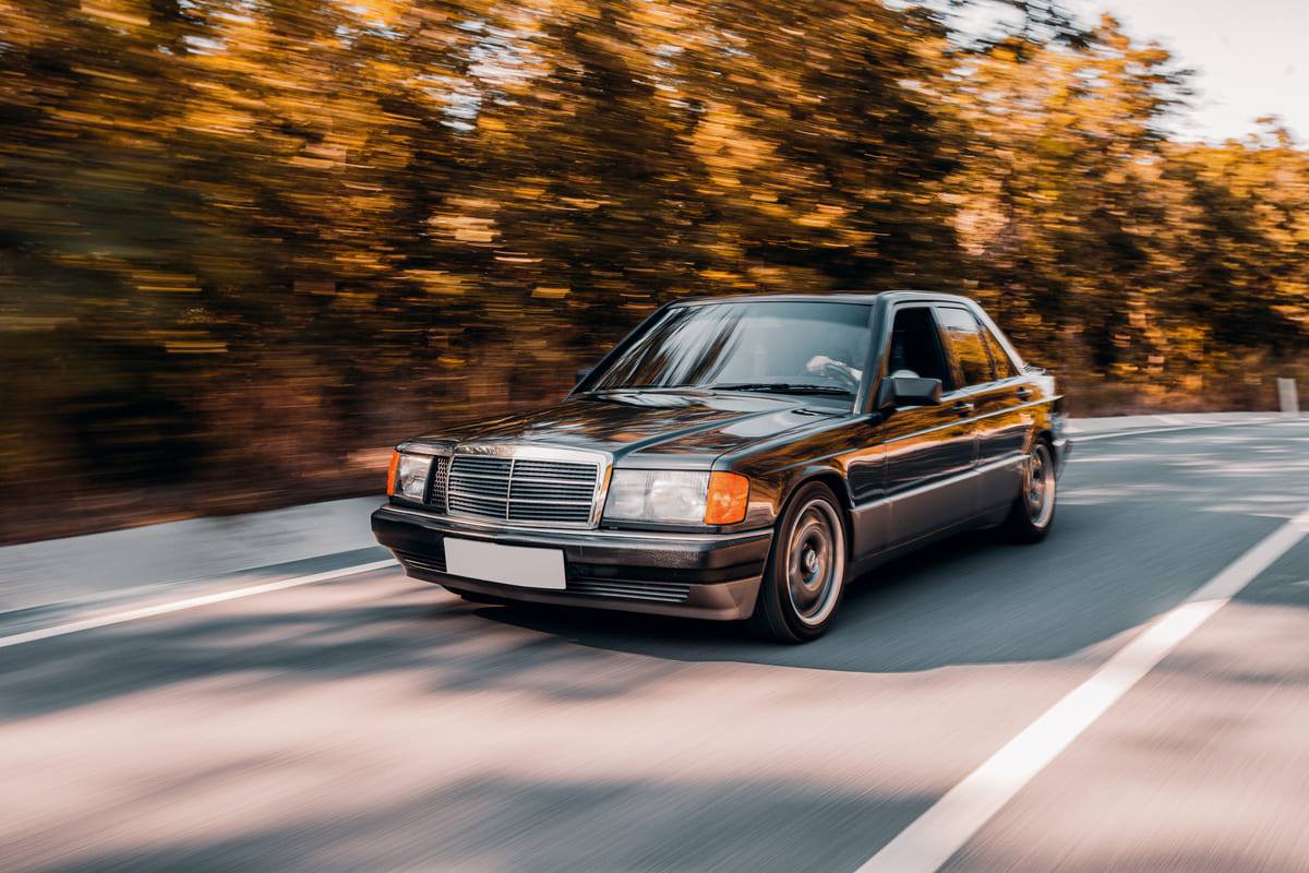 Mercedes-Benz preto em movimento na estrada, modelo famoso entre os nomes dos carros antigos.