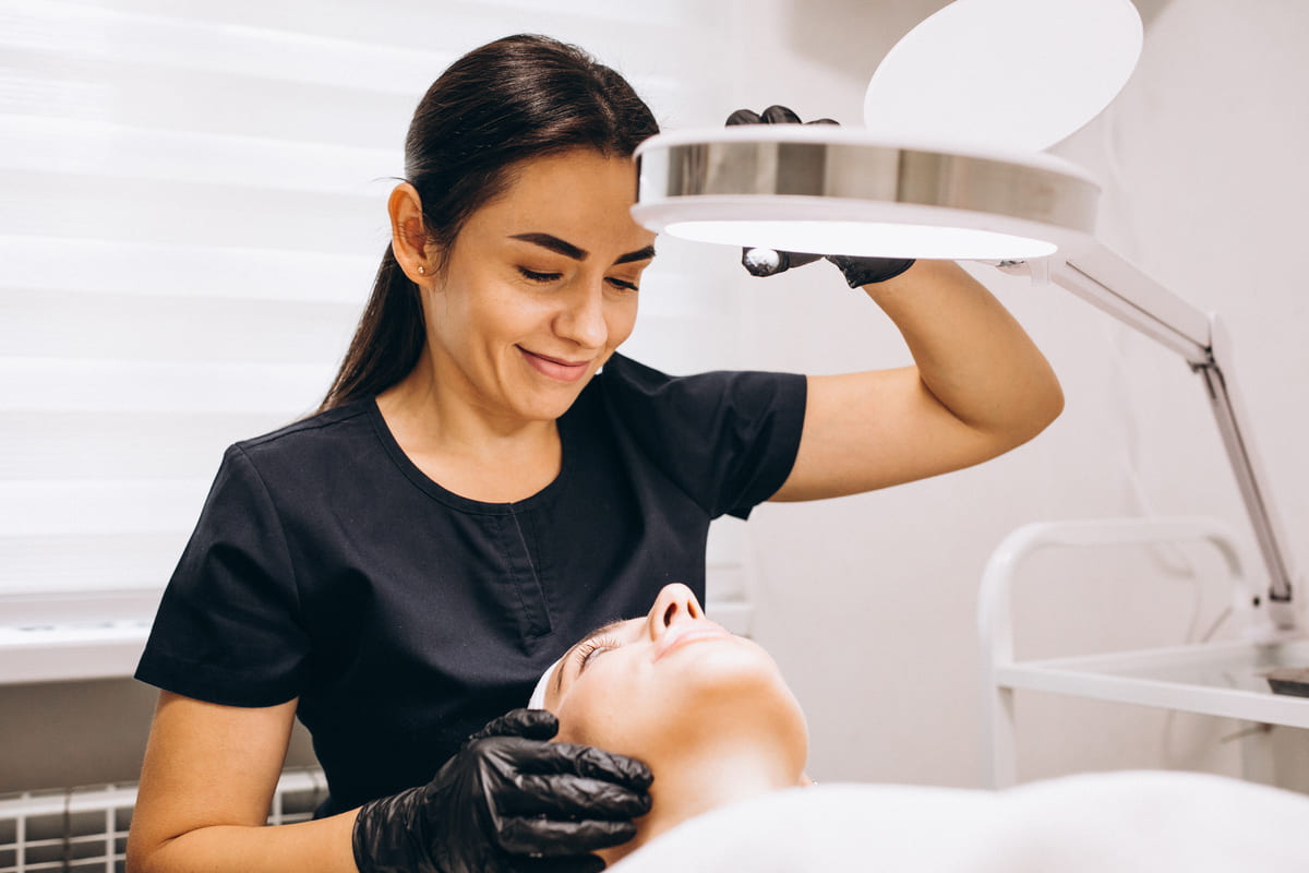 Profissional avalia rosto de paciente sob a luz antes do skinbooster.