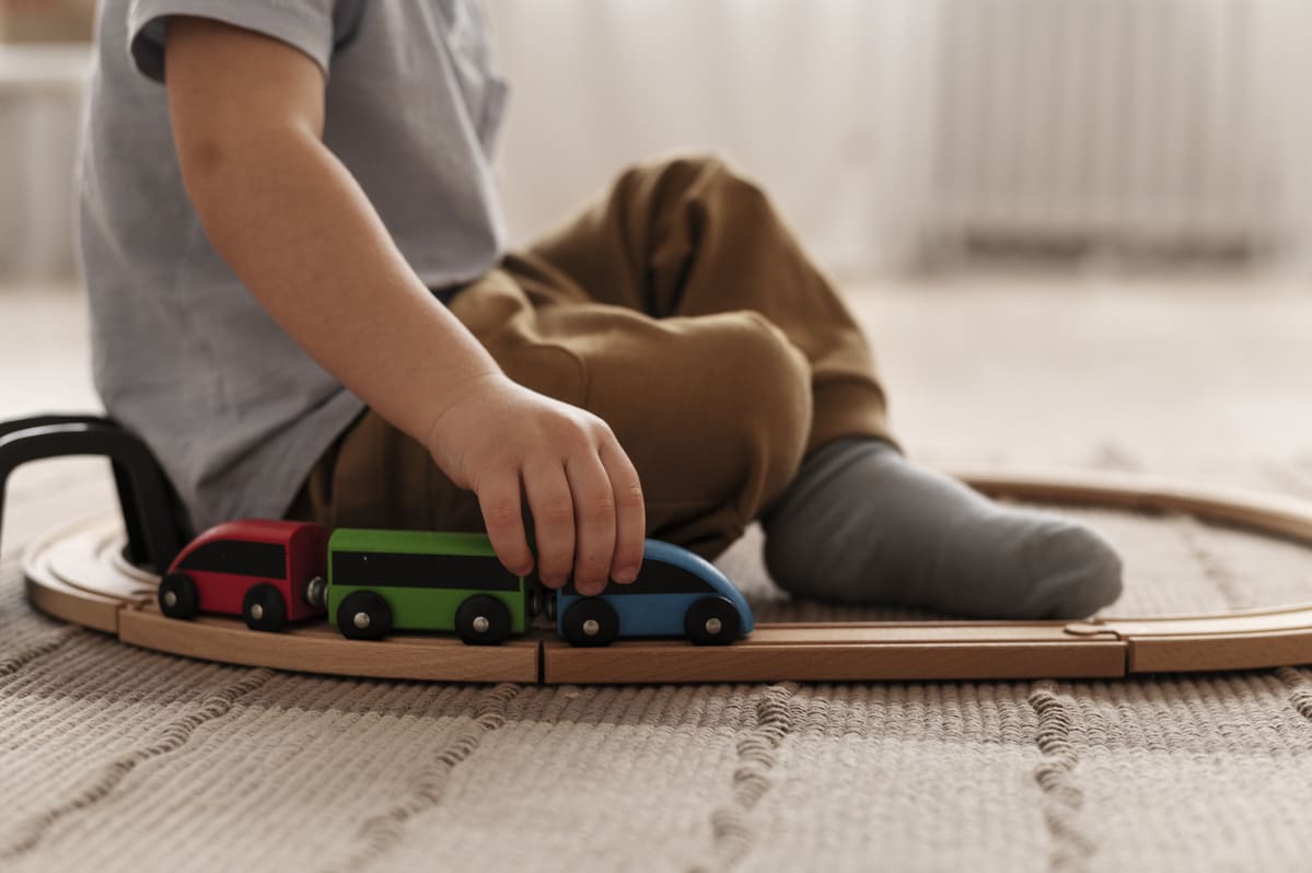 Criança brincando com trem de madeira, opção de brinquedos para o dia das crianças.