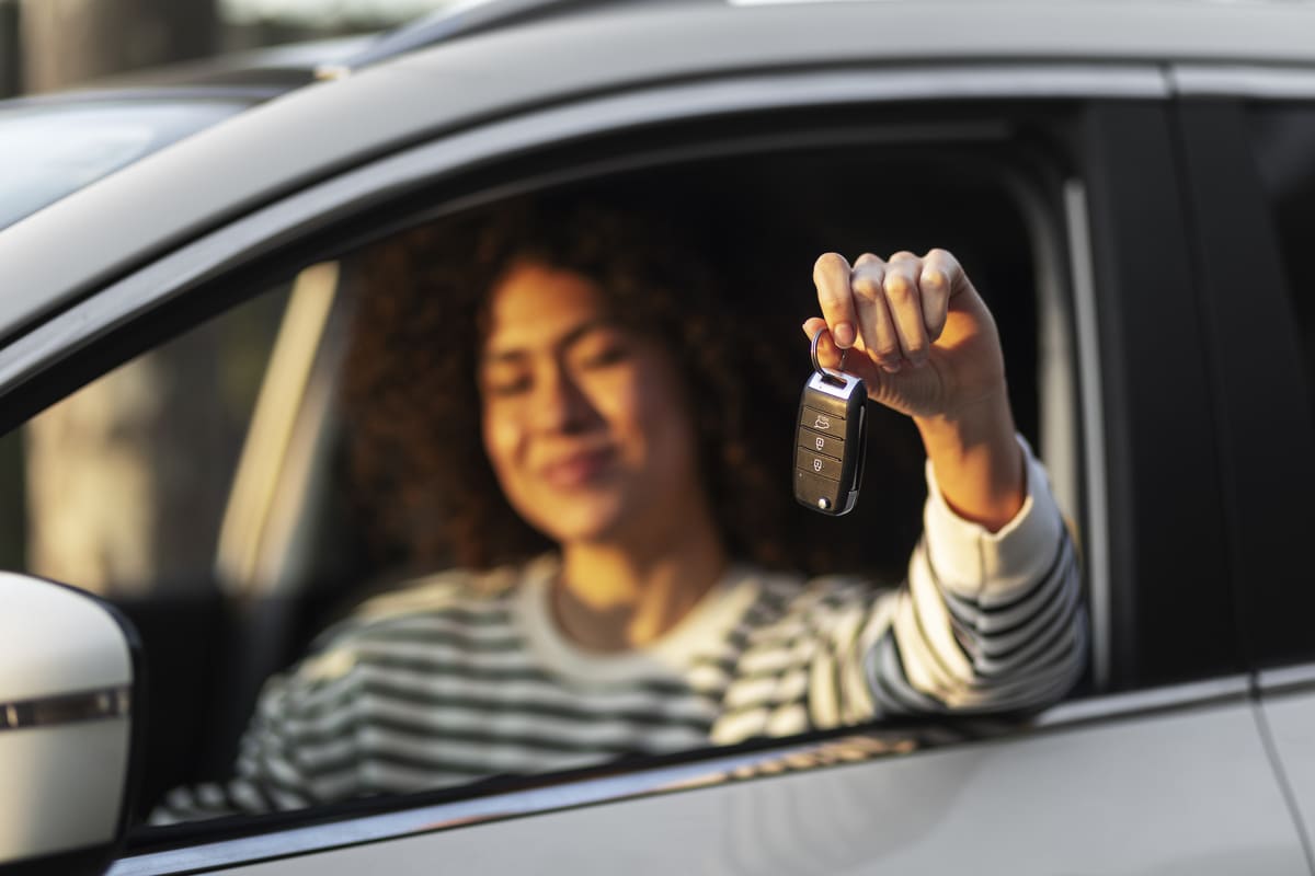 Jovem condutora mostrando a chave de um dos melhores carros para jovens.