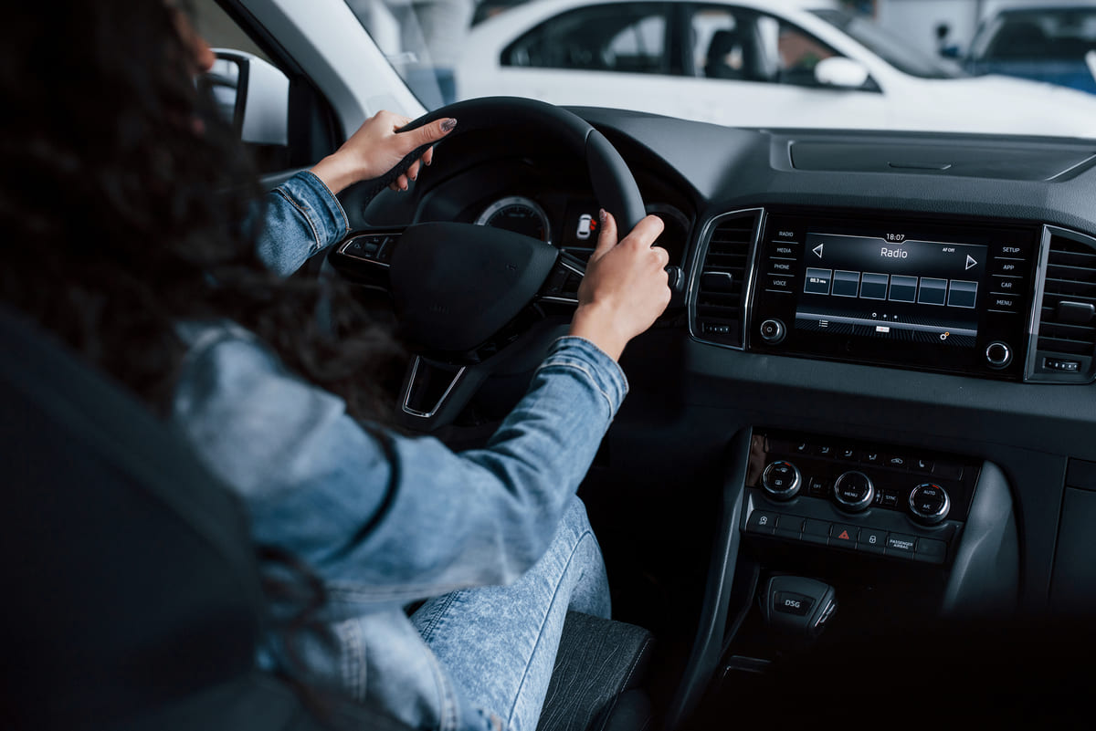Mulher fazendo test drive para verificar o estado e a garantia de carro usado.