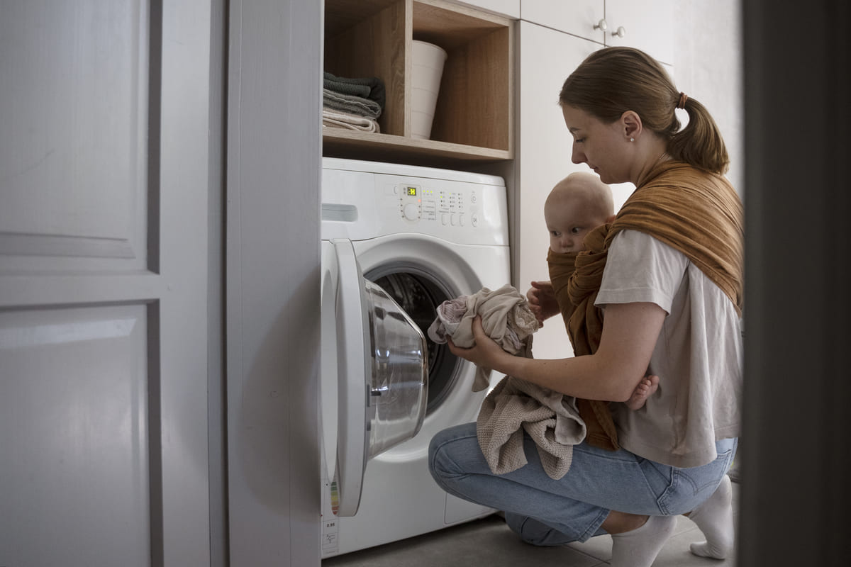 Mulher usando máquina de lavar com bebê ao avaliar qual a melhor máquina de lavar roupas.